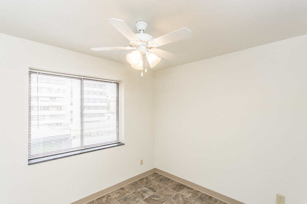 an empty room with a ceiling fan and a window