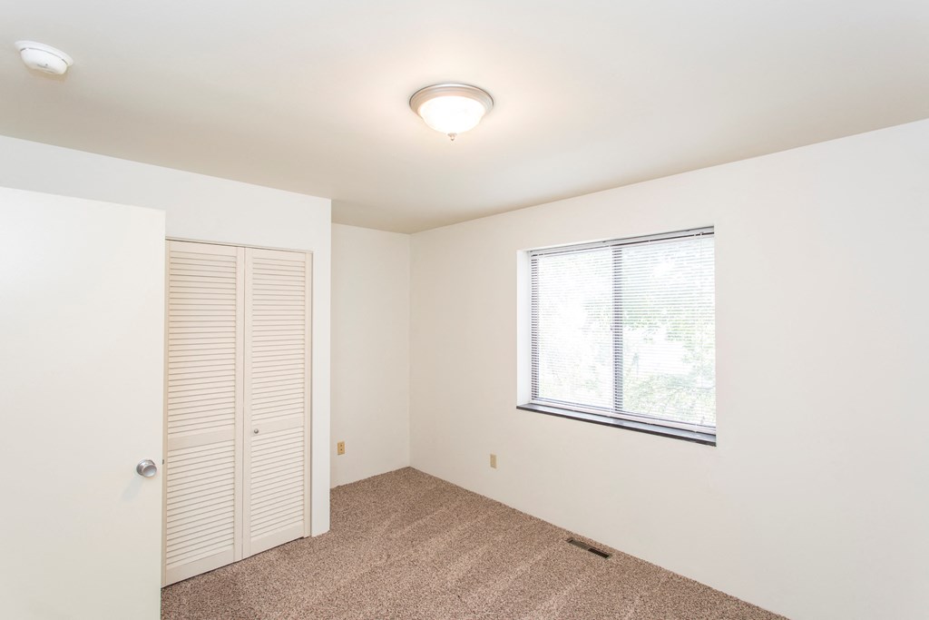 an empty room with a window and a closet