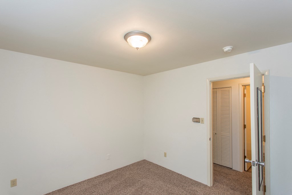 a bedroom with white walls and a door to a closet