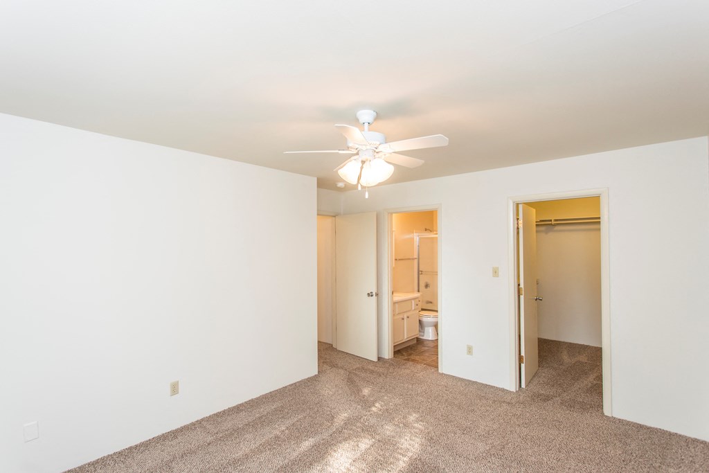 a living room with a ceiling fan and a door to a bathroom