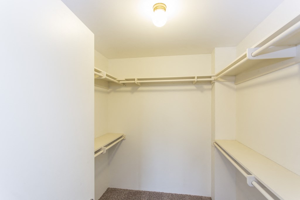 a walk in closet with empty shelves and a light on the ceiling