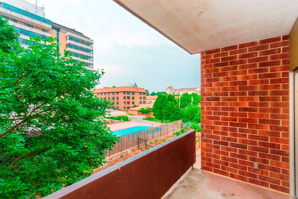 a balcony with a view of a pool and trees