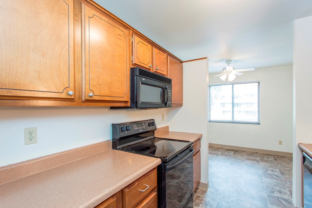 an empty kitchen with wood cabinets and a stove and microwave