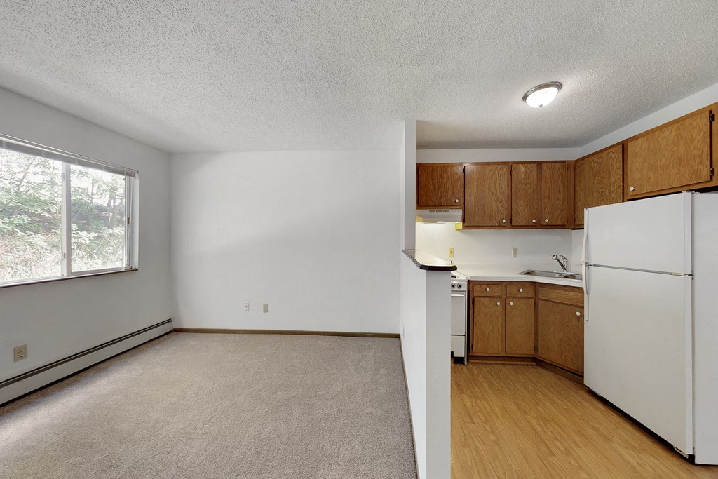 an empty kitchen with white appliances and wood flooring