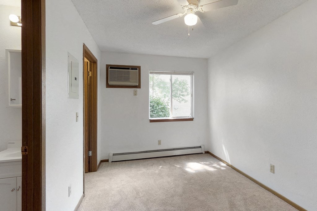 an empty living room with a ceiling fan and a window