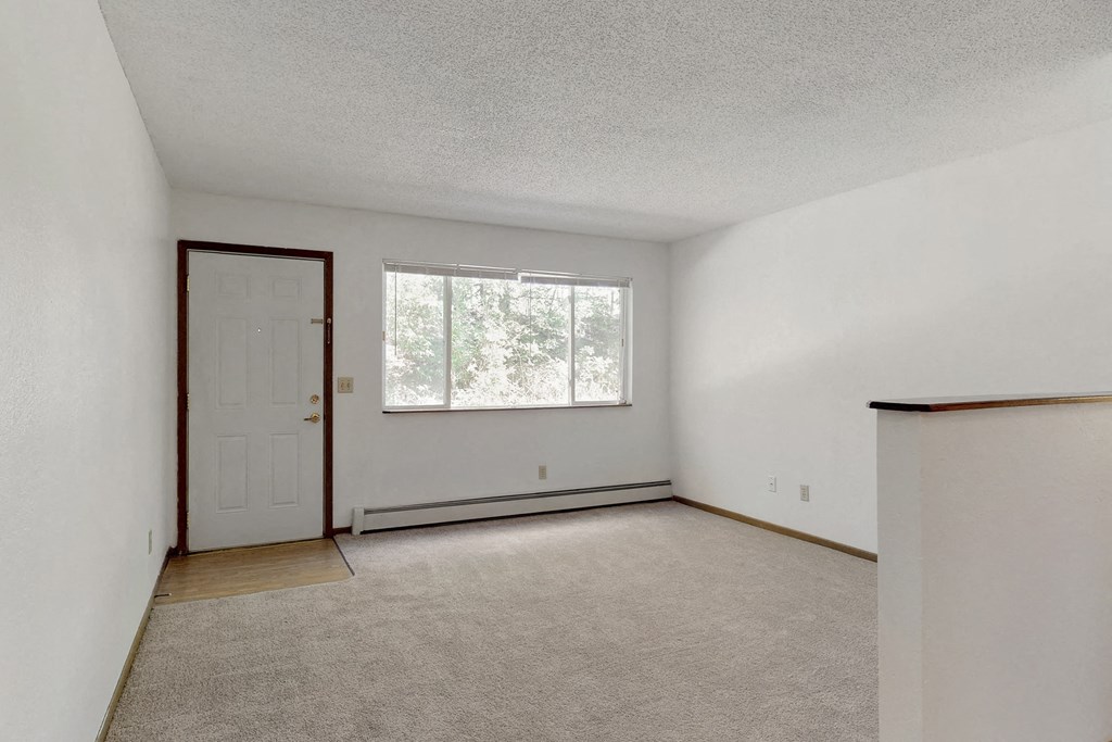 an empty living room with a white door and a window