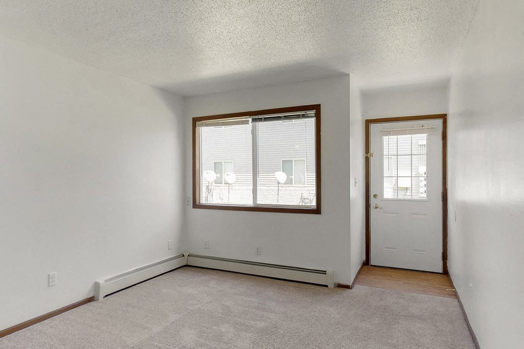 an empty living room with a window and a door