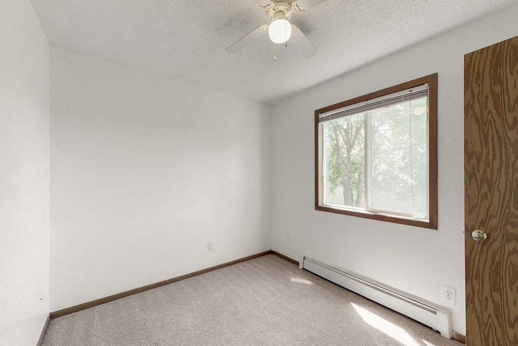 a bedroom with white walls and a window and a ceiling fan
