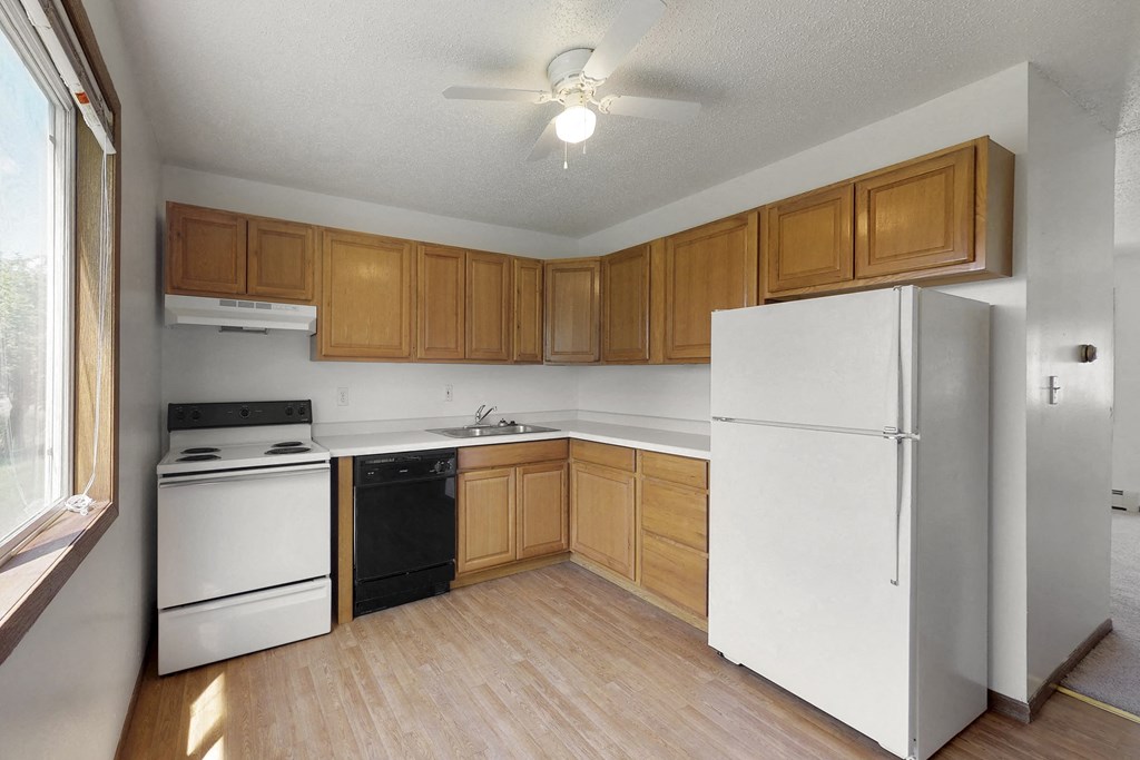 an empty kitchen with white appliances and wooden cabinets
