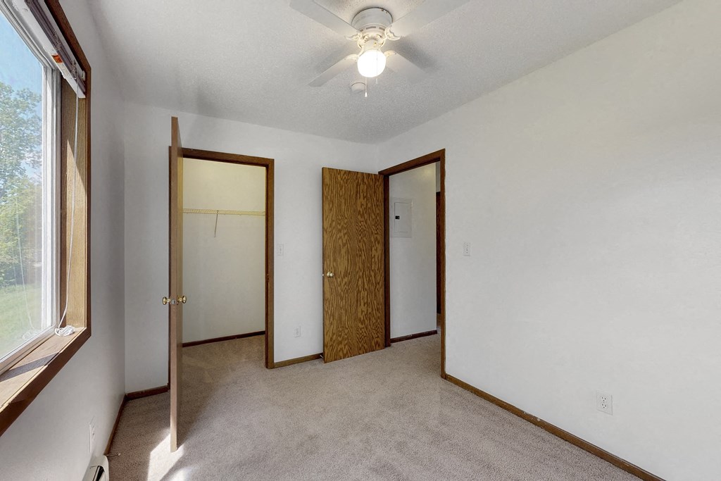 a bedroom with two doors and a ceiling fan