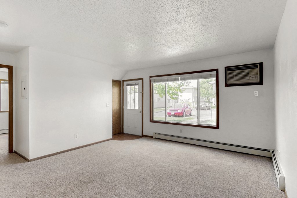 an empty living room with a large window and white walls