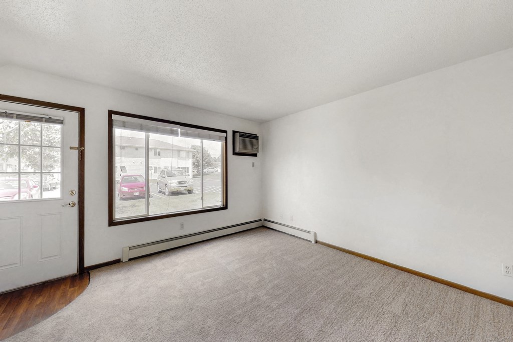 an empty living room with a large window and a door
