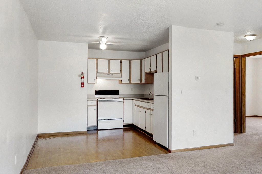 an empty kitchen with white appliances and white cabinets