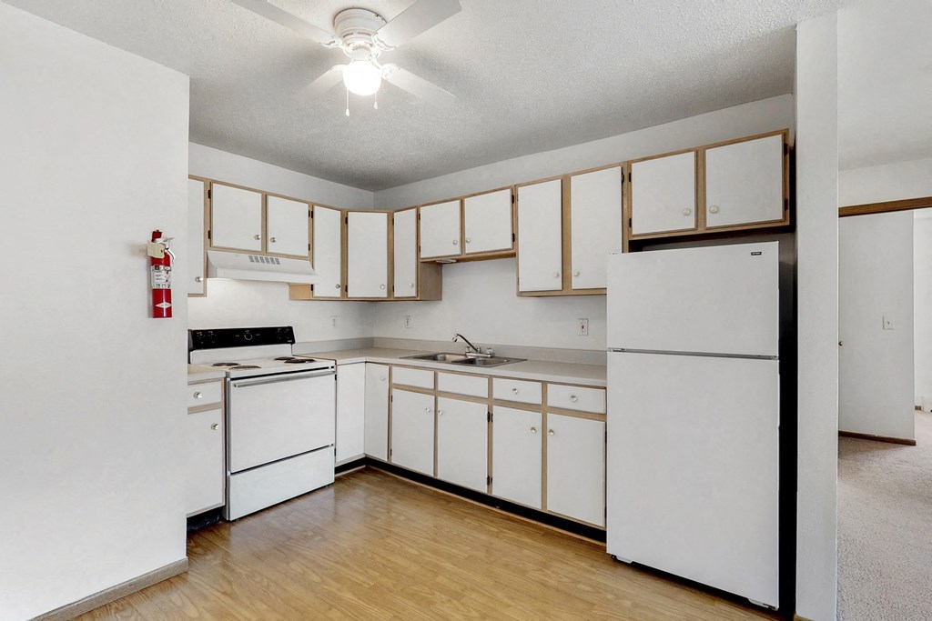 an empty kitchen with white appliances and white cabinets