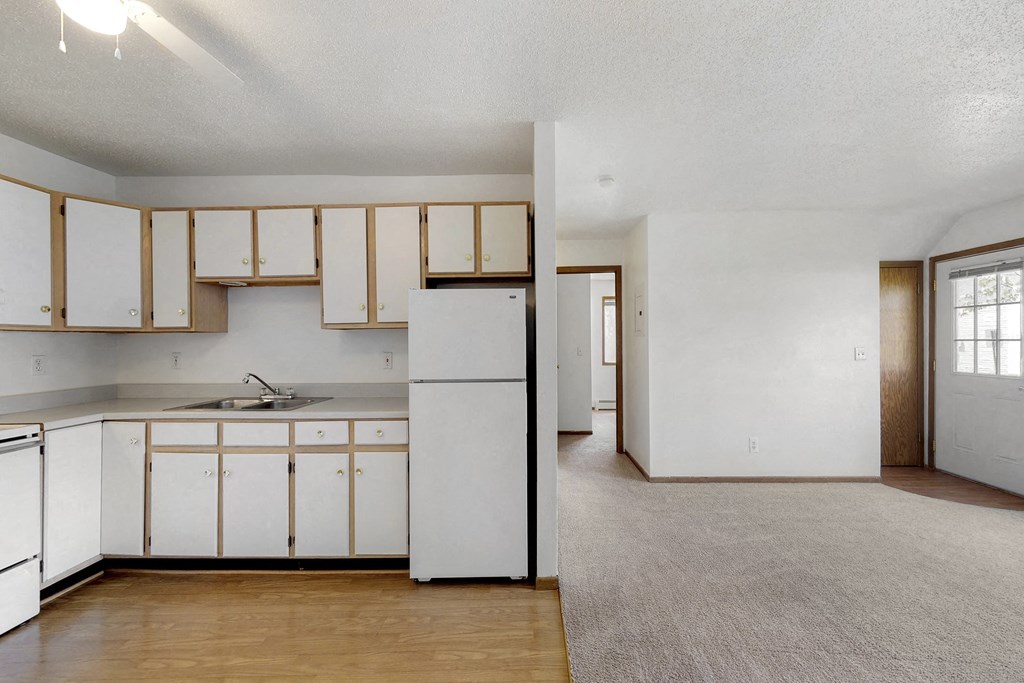 an empty kitchen with white cabinets and a white refrigerator