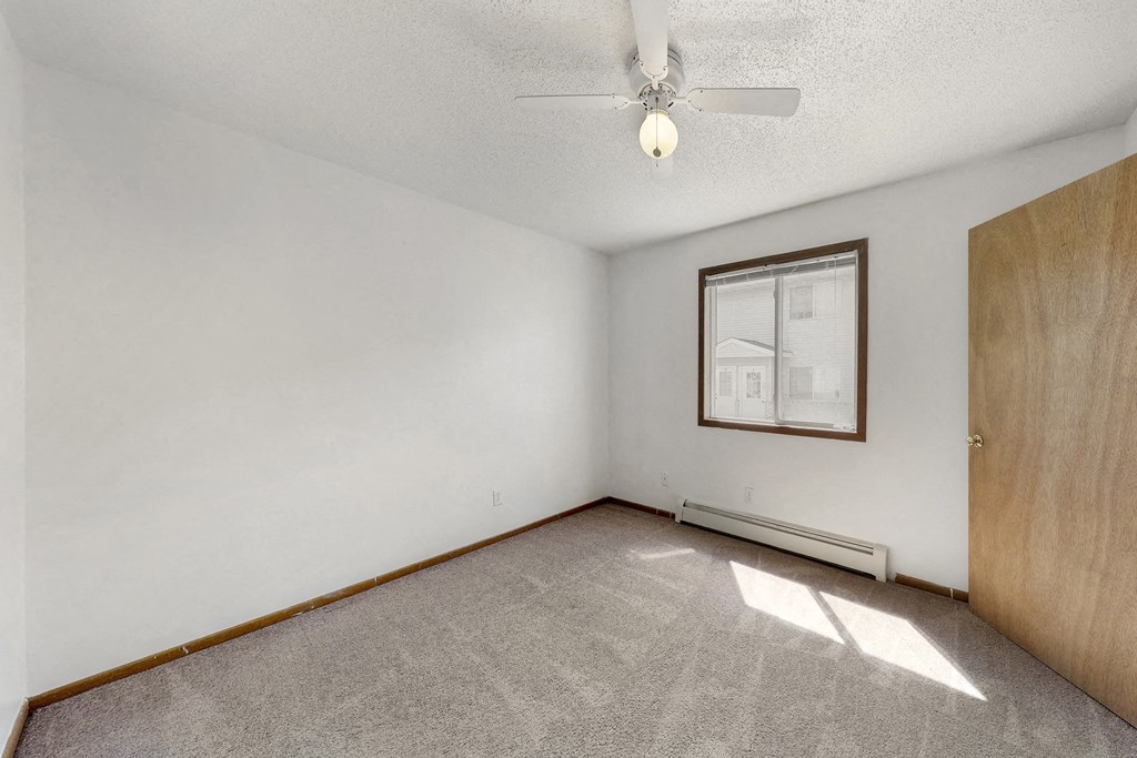 an empty living room with a ceiling fan and a window