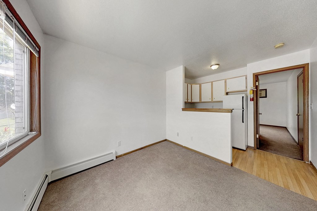 the living room and kitchen of an empty home with white walls and wood floors