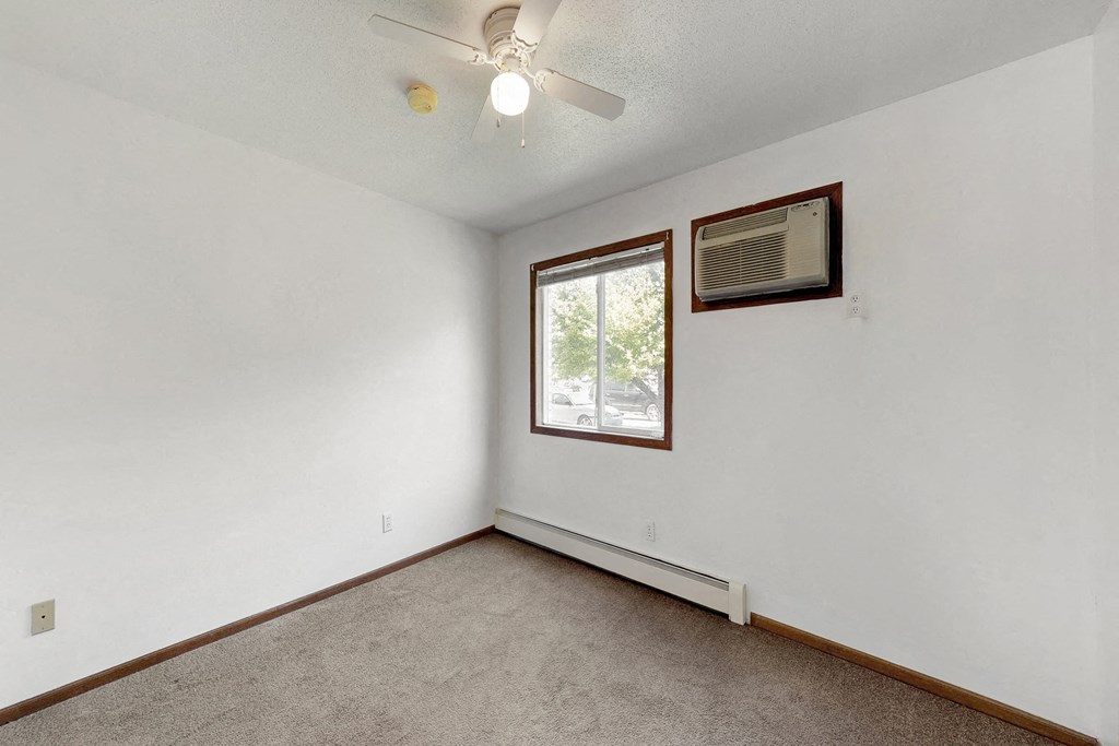 an empty living room with a ceiling fan and a window