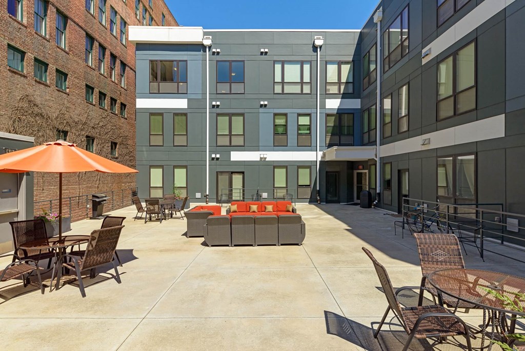 a courtyard with furniture and an umbrella in front of a building