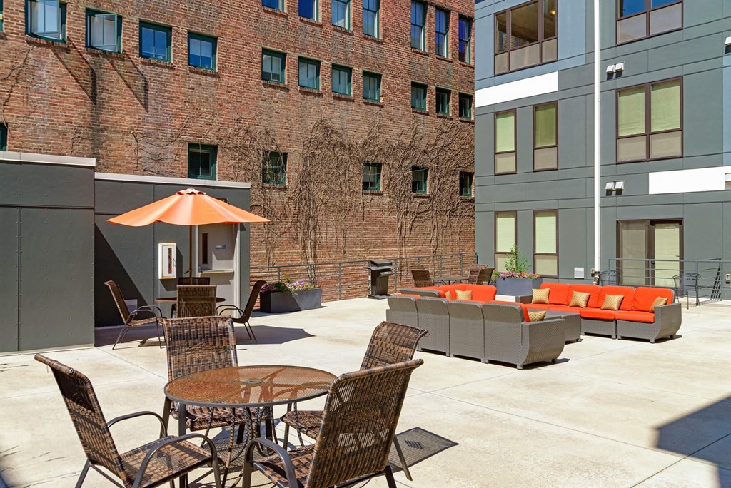 an outdoor patio with tables and chairs and a brick building