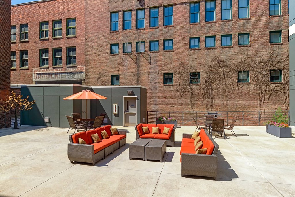 a patio with couches and chairs in front of a brick building