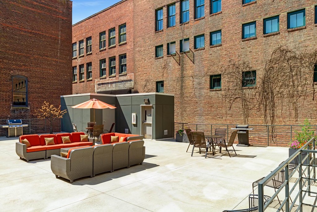 a patio with couches and chairs in front of a brick building