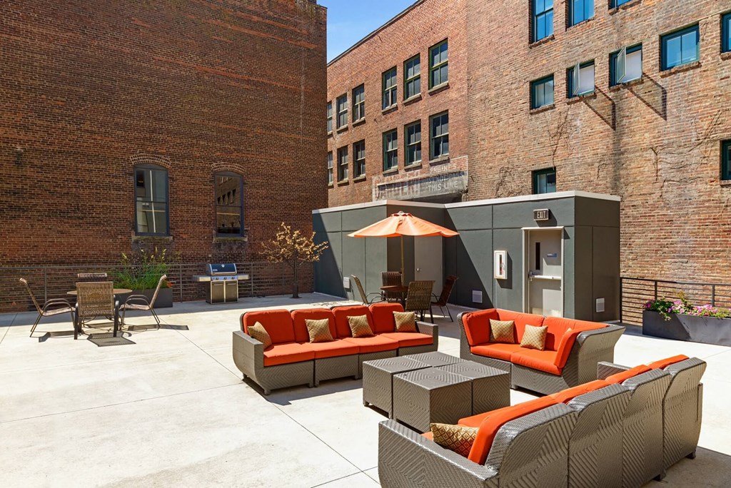a patio with couches and chairs and an umbrella in a courtyard
