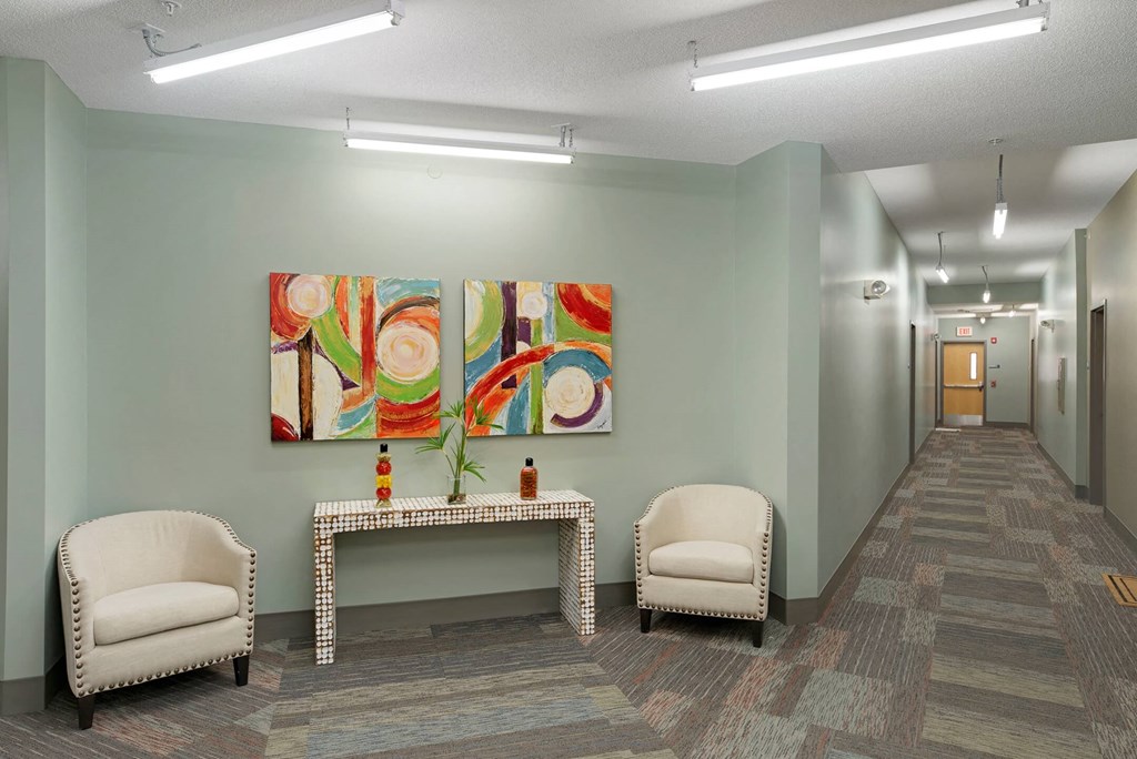 a lobby with a table and chairs and a painting on the wall