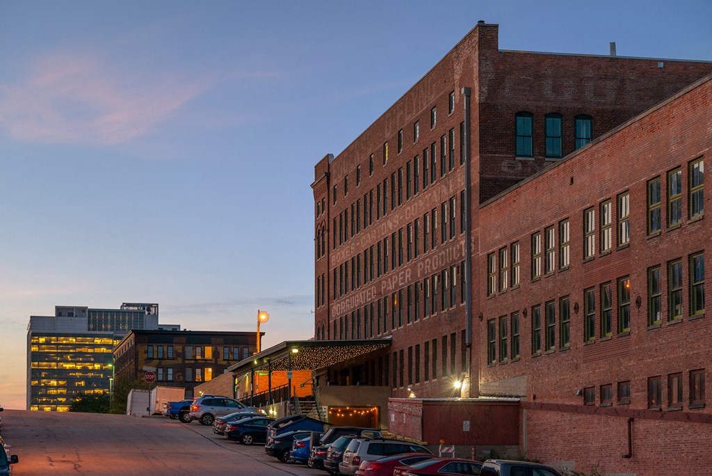 a large brick building with cars parked in front of it at dusk