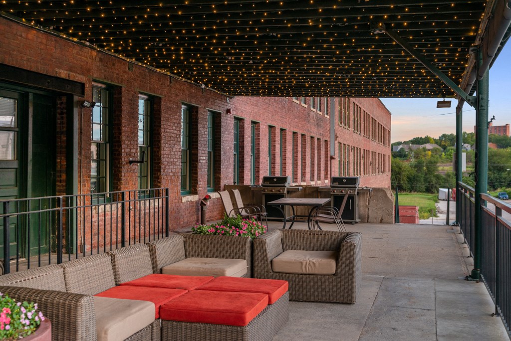 a covered patio with tables and chairs and a grill