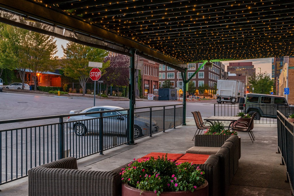 a view of a city street from a porch with benches and a stop sign