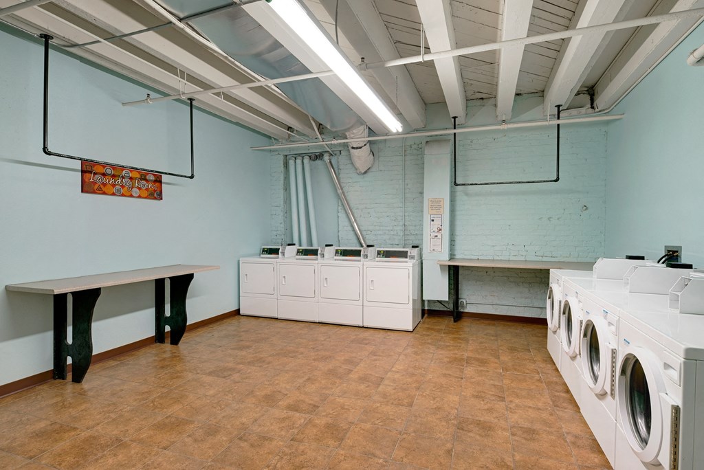 a laundry room with washers and dryers and a row of washing machines