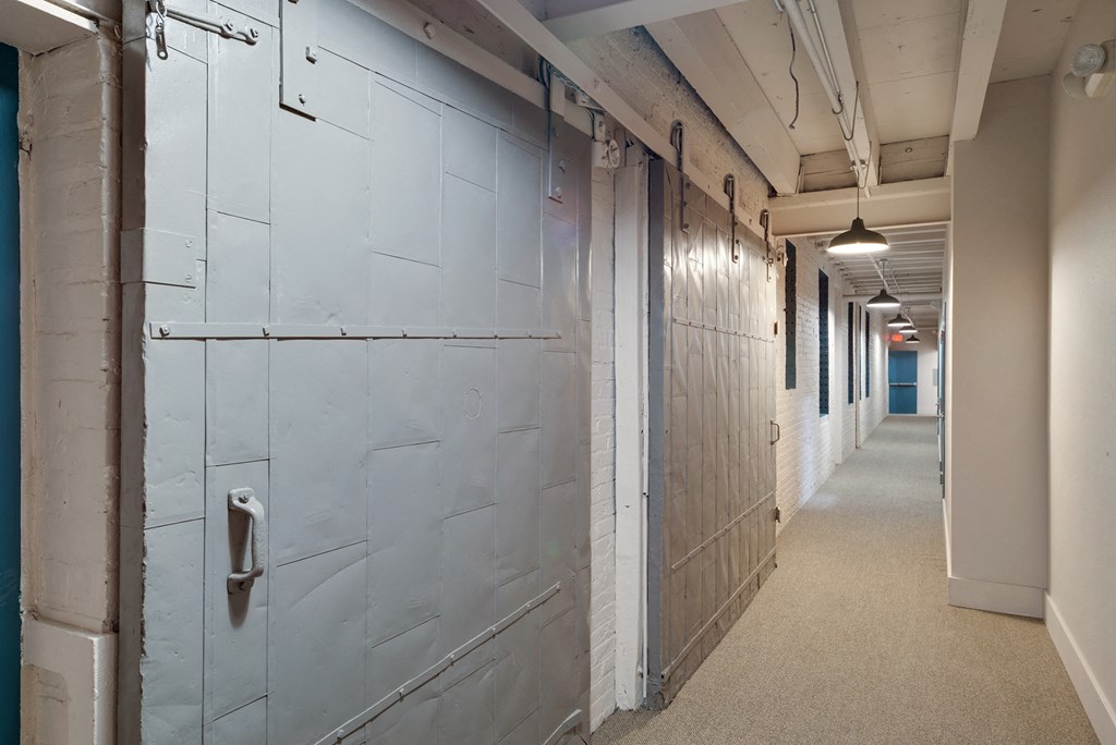 a long hallway with white walls and a row of lockers