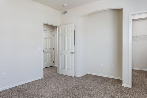 an empty bedroom with a closet and an open door