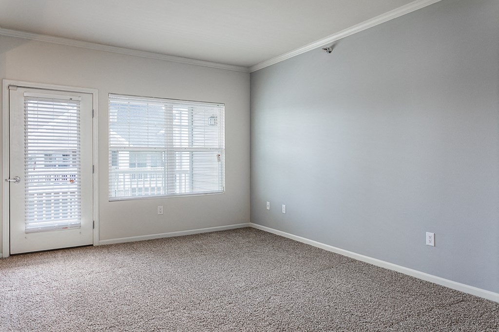 an empty room with carpet and a door and window