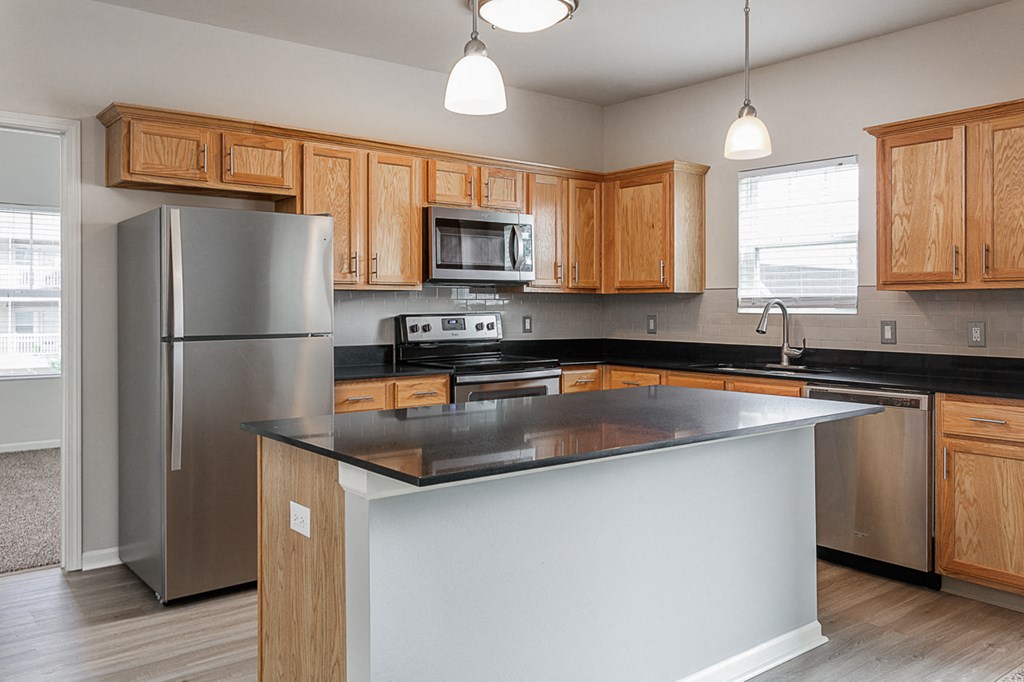 an empty kitchen with an island and stainless steel appliances