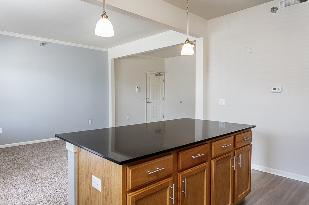 an empty kitchen with wooden cabinets and a black counter top