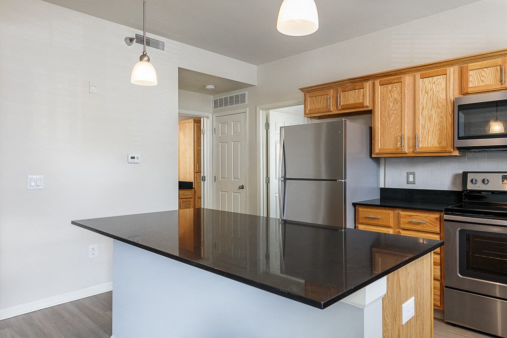 a kitchen with a black counter top and a stainless steel refrigerator
