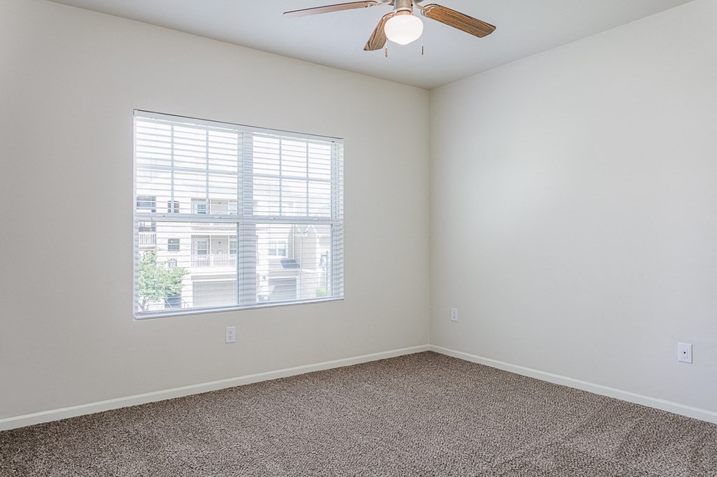 an empty room with a window and a ceiling fan
