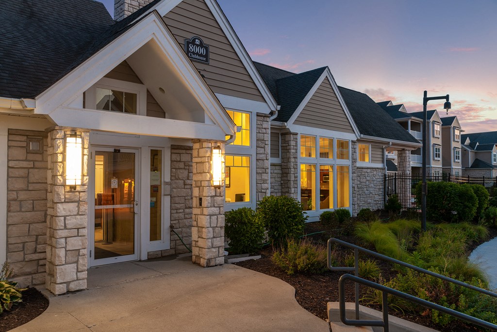 a row of homes with a sidewalk in front of them at dusk