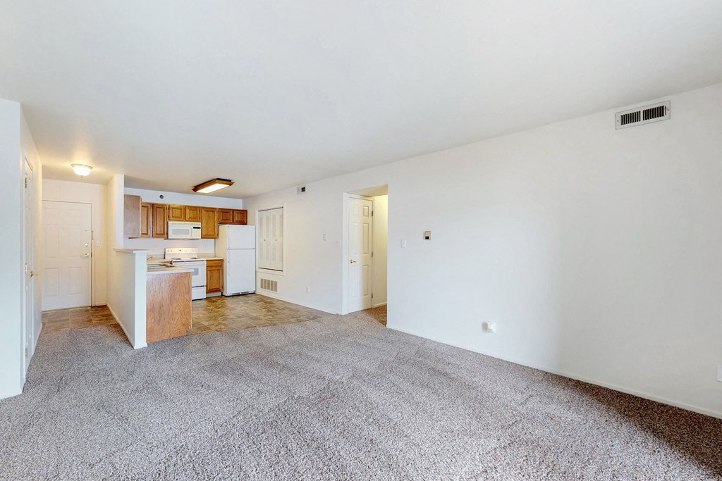 an empty living room and kitchen with white walls and flooring