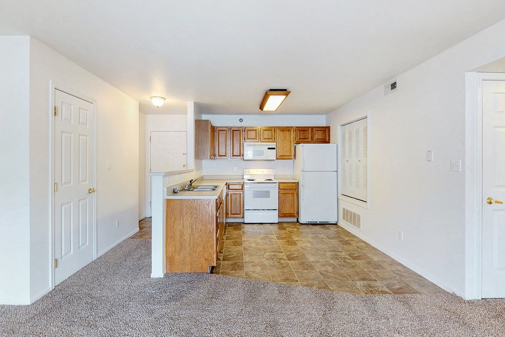 an empty kitchen with white appliances and wood cabinets
