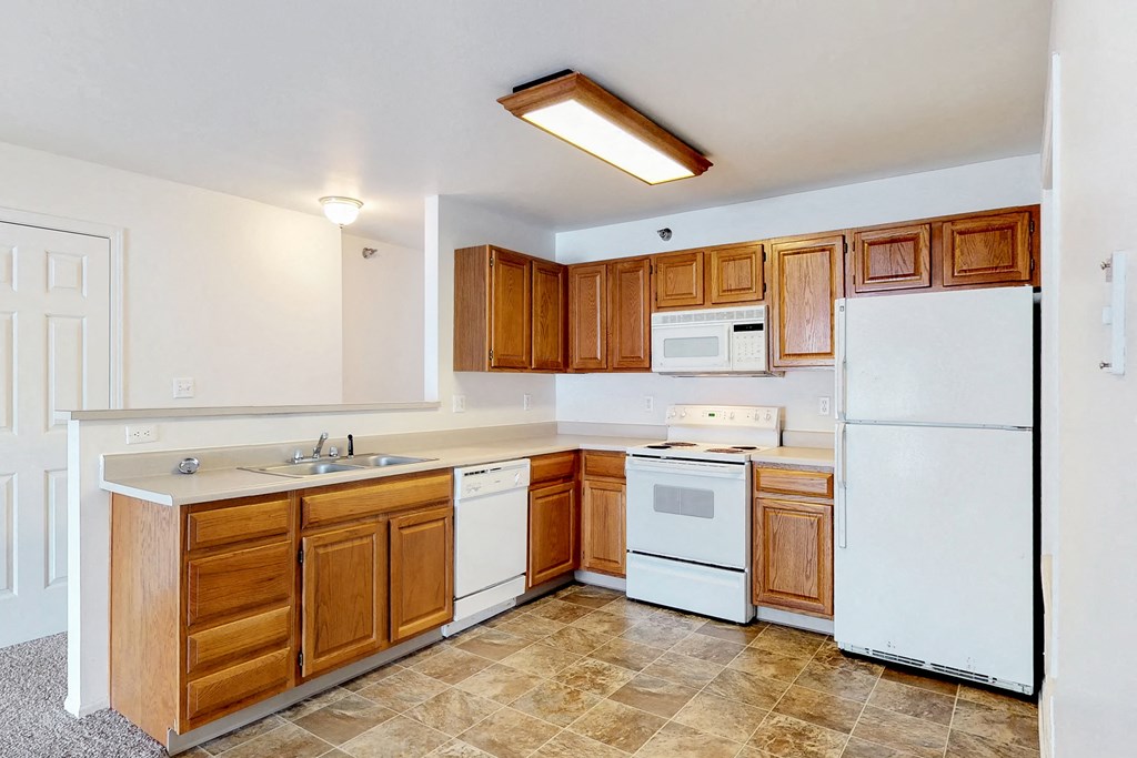 an empty kitchen with white appliances and wooden cabinets
