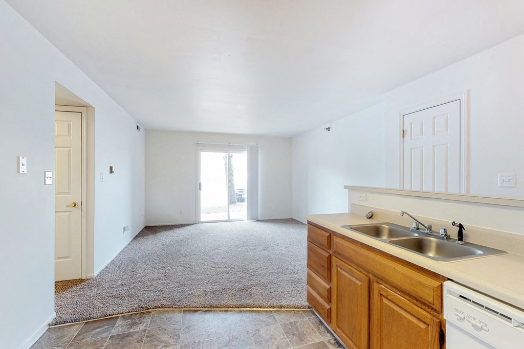 an empty kitchen with a sink and a door to a living room