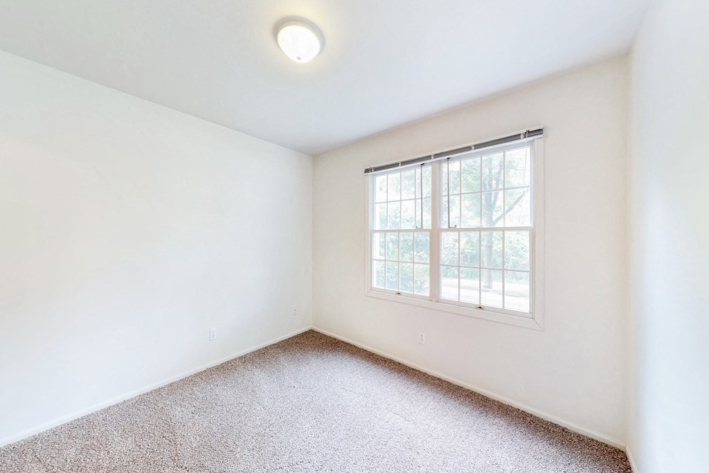 an empty room with a window and carpeting