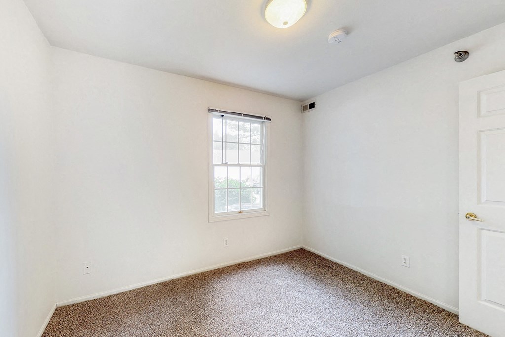 an empty room with white walls and a window