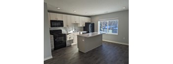 an empty kitchen with white cabinets and black appliances