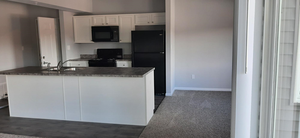 a kitchen with white cabinets and a black refrigerator