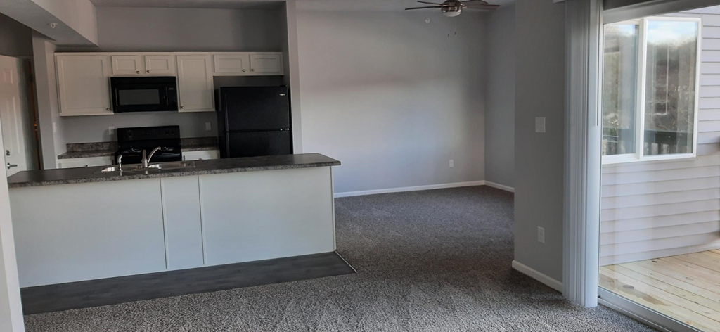 a kitchen and a living room with white cabinets and a counter