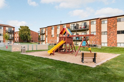 A playground with a yellow slide and a red and yellow structure.